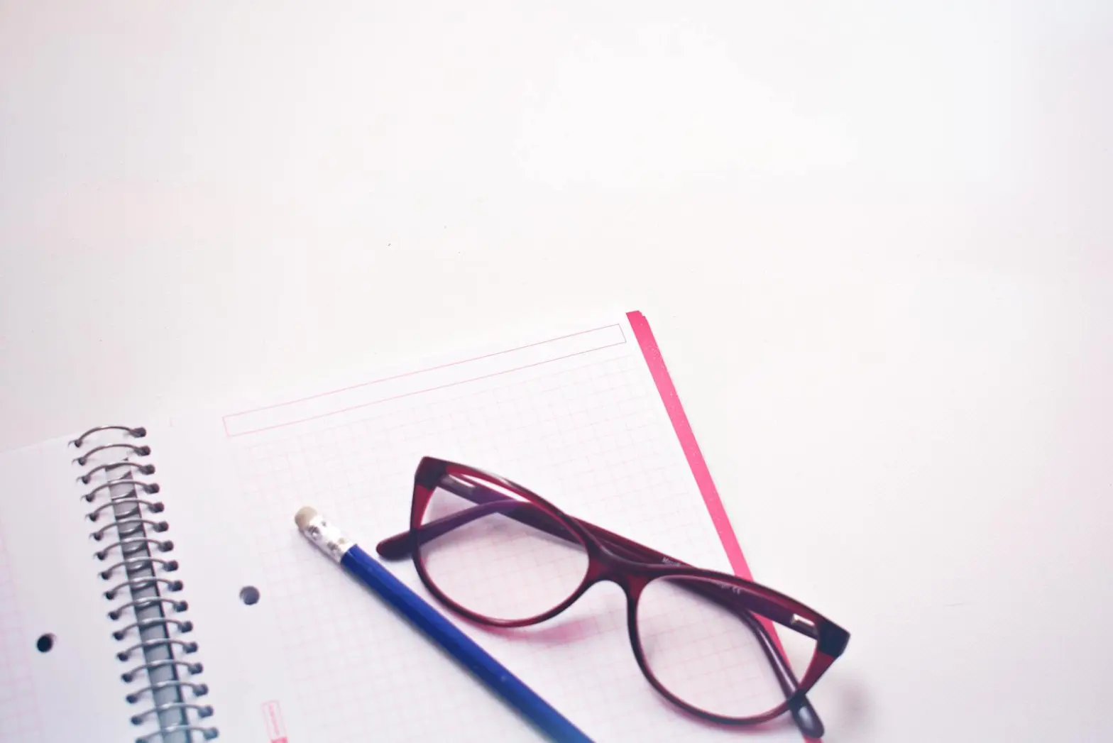 Eyeglasses resting on graph paper notebook with pencil, perfect for study or writing concepts.